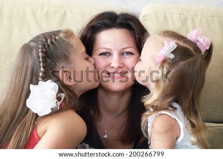 mother and her two little daughter kiss her close up portrait