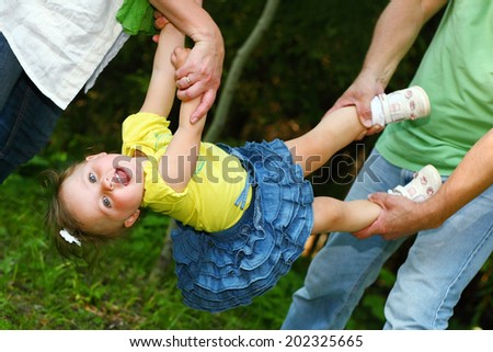 little girl hanging in parents hands
