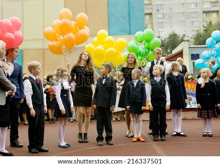 MOSCOW, SEPTEMBER 1, 2014: The first school day for the first grade kids on the September 1 2014. Unidentified senior pupils with first grade  prepare to send colored balloons to the sky on the September 1 2014.