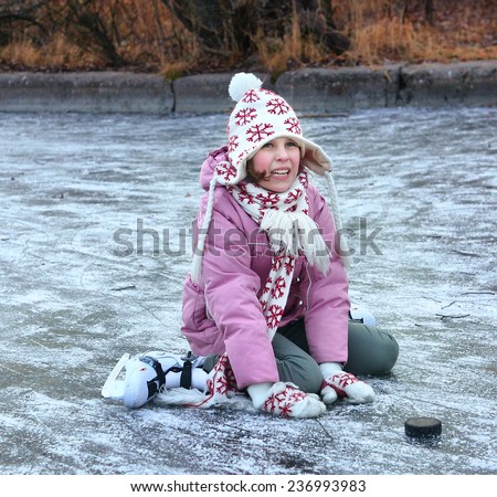 beautiful happy preteen girl figure skating in open winter skating rink fall down hurt her leg