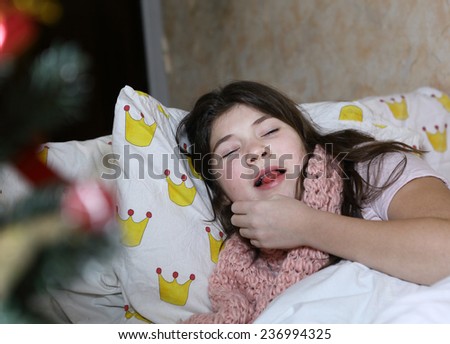 beautiful teen girl with long dark hair sick in bed in christmas eve sniffing