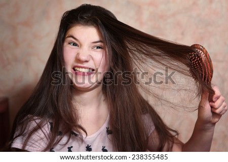 beautiful teen girl try comb her long dark thick hair
