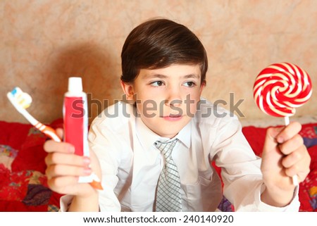 happy school boy make choice between candy and toothbrush