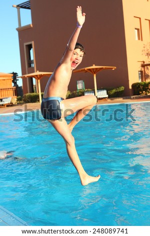 preteen little boy jump into open air swimming pool