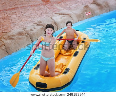 siblings preteen girl and boy in rubber boat with raw in egyptian open air water park