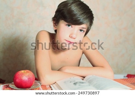 handsome preteen boy reading book with apple