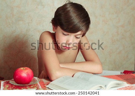 handsome preteen boy reading book with apple