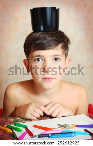 preteen handsome boy with blenda on his head drawing with colored pencils and crayons