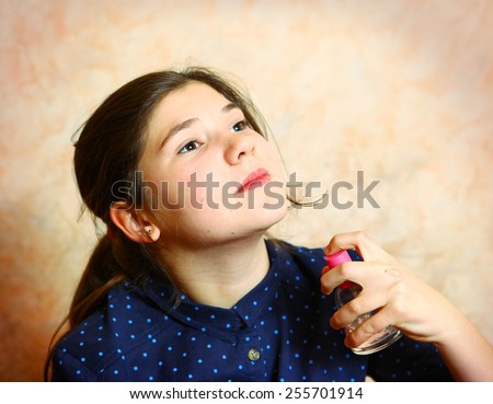 preteen cute girl with long dark hair in pony tail smell new perfume