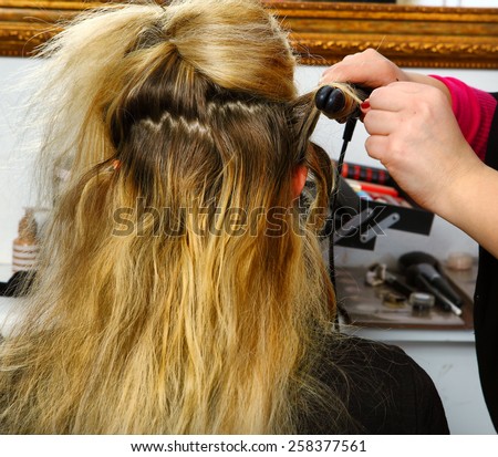 hair dresser hands make curls with curling tongs close up photo