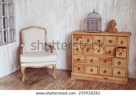 wooden chest of drawers in shabby styled room with bird cage and Mozart bust