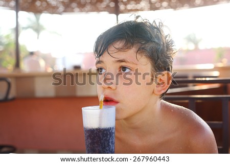 preteen handsome boy drink cola cocktail at the pool bar in sea resort hotel