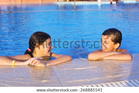 siblings boy and girl play in open air swimming pool at the egyptian sea resort hotel