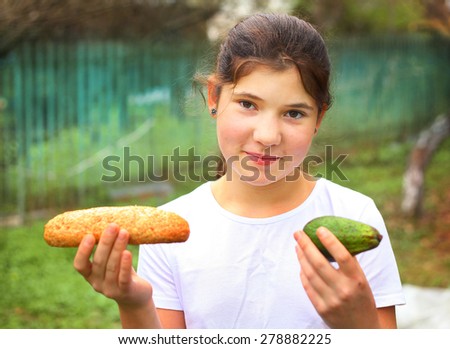 happy teenager girl with natural healthy food - grain bread loaf and avocado on the green country garden background