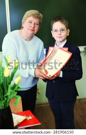 MOSCOW, MAY 26, 2015: Graduation in the primary school in Moscow, May 26. Graduating boy with his teacher  gets diploma and then go to the middle school.