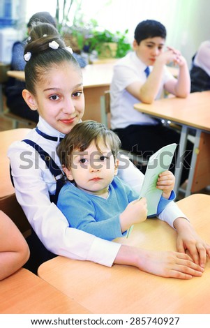 MOSCOW, MAY 26, 2015: Graduation in the primary school in Moscow, May 26. Graduating girl with her little brother  in the classroom gets diploma and then go to the middle school.