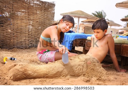 preteen siblings brother and sister have fun on sand beach play with sand
