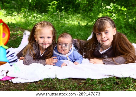 preteen blond little sister and baby boy brother lay on the summer park grass