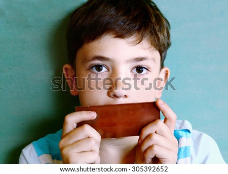 preteen handsome boy with chocolate piece isolated on blue
