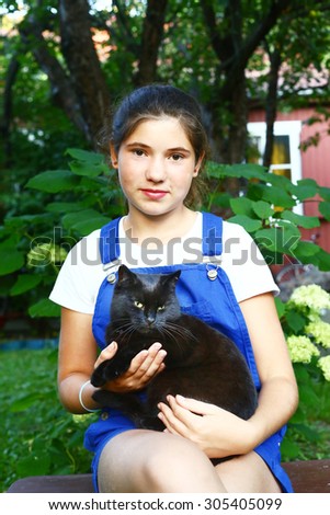 beautiful teen girl with black cat on her knees