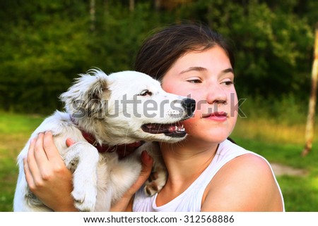 teenager girl play with white puppy on the summer forest background