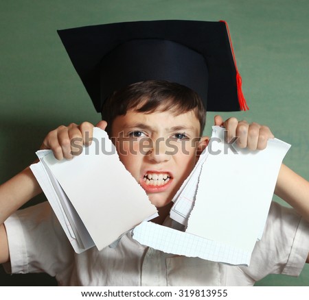 school boy in graduation cap rebel against hard learning