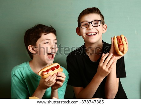teenager school boys cooking eat hot dog happy smiling laughing closeup portrait on blue wall background