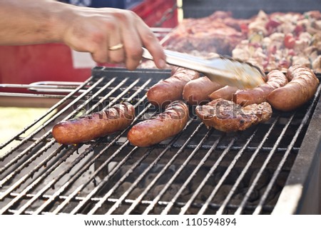 a man grilling various types of meat on the grill