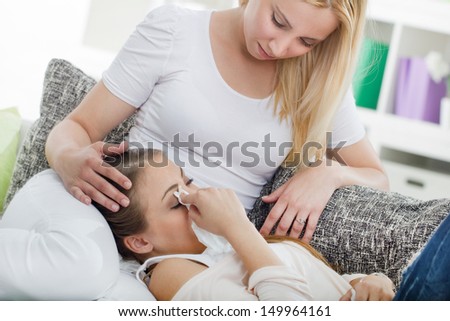 Friend comforting her crying friend at home on the couch