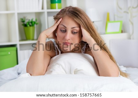 lonely young woman lying in bed and thinking something
