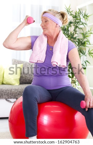 Senior woman sitting on gym ball, and exercise