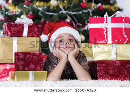 cute caucasian boy dreaming about presents at christmas time