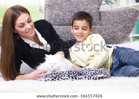 Mom and son lying on the floor and caress white Persian cat