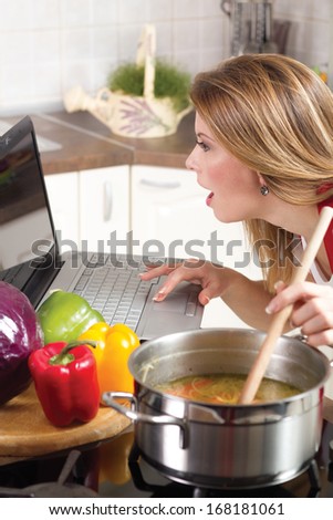 funny modern housewife using a laptop while cooking