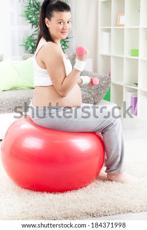 pregnant woman  exercises using dumbbells at home