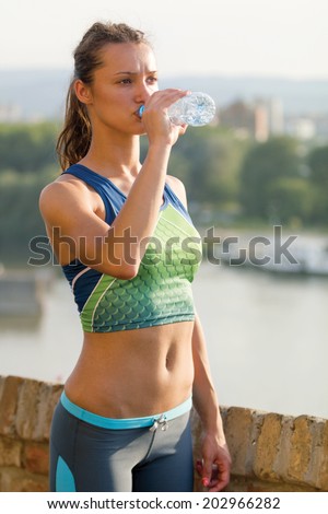 sporty woman exercising outdoor on sunny day and drink water