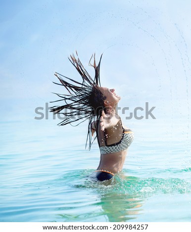 Woman splashing water with her hair in the sea
