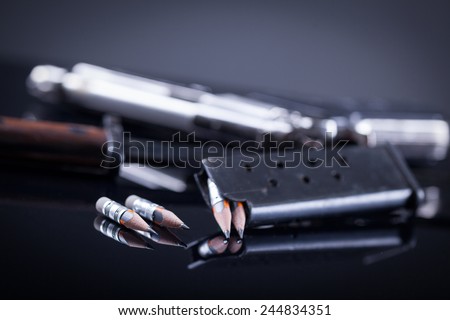 magazine knife, pen in the form of bullet and blurred gun in the background