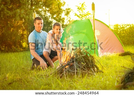 happy family near campfire roasting sausages