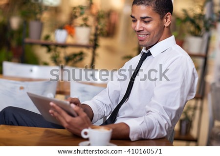 smiling businessman in the restaurant  working on ipad