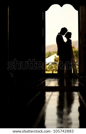 Asian groom and bride embrace in front of boutique door