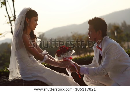 Asian groom give flower to his bride