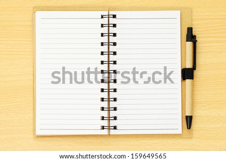 Note book paper with brown pen on wooden background
