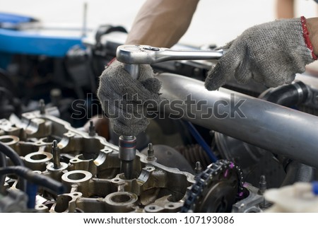 Automotive adjusting an engine in workshop