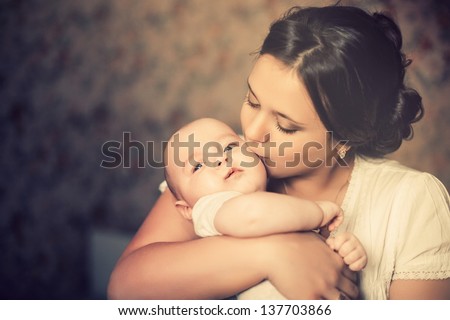 Young Mother Kissing Her Little Newborn Baby