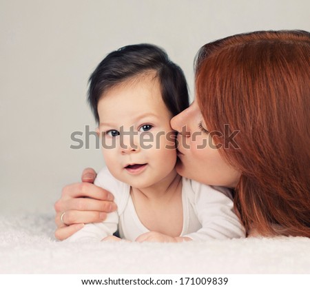 mother kissing her little newborn baby
