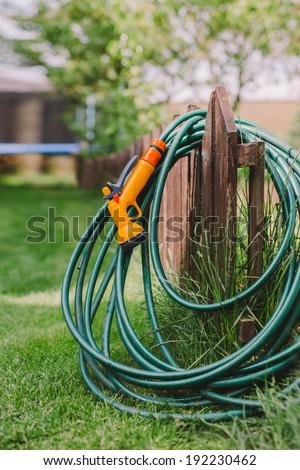 a green rubber garden hose with nozzle outdoor