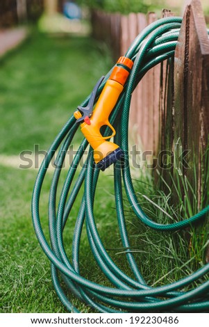 a green rubber garden hose with nozzle outdoor