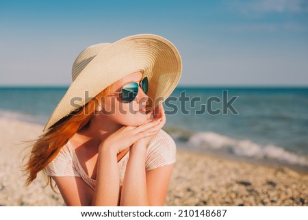woman in a wide sun hat enjoying the summer sun at the beach