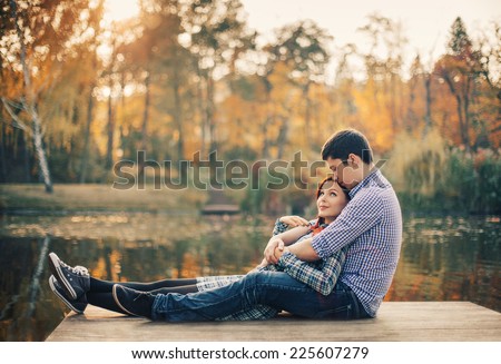 Romantic couple relaxing on the river dock in autumn park